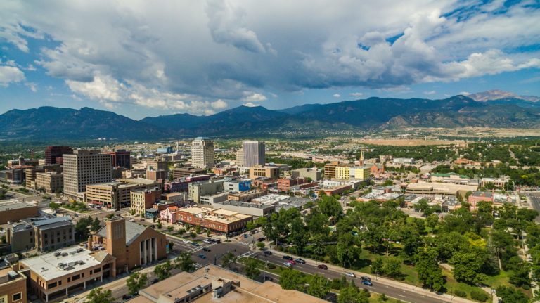 Aerial view of downtown Colorado Springs overlooking Acacia Park with Pikes Peak in the distance.