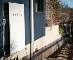 Tesla Powerwall installed on the side of a navy blue house