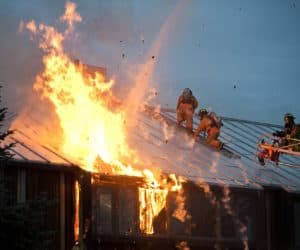 Fire fighters on top of a building with rooftop solar panels that are lit on fire.