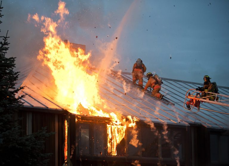 Fire fighters on top of a building with rooftop solar panels that are lit on fire.
