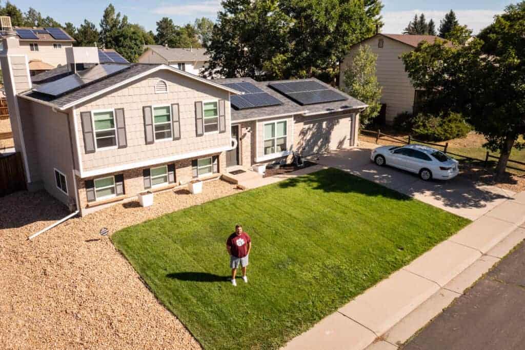 Man standing in the garden in front of a house with solar panels on the roof in Aurora, Denver