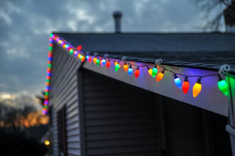 A zoomed-in photo of colorful christmas lights mounted on the edge of a home's roof.