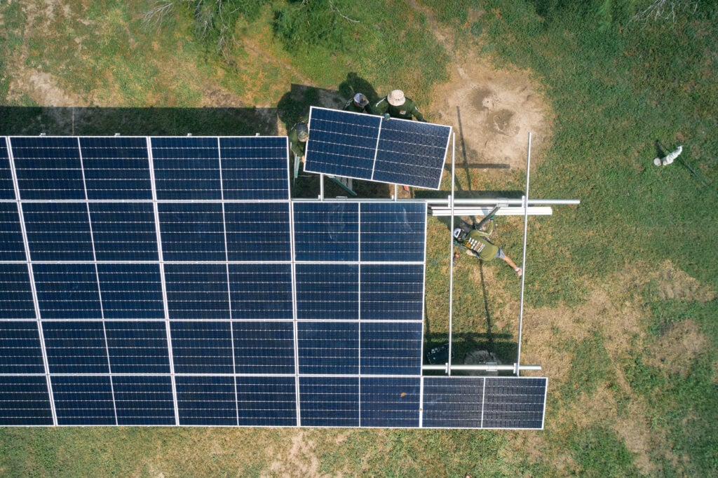 top-down aerial view of solar panel being added to ground mount frame