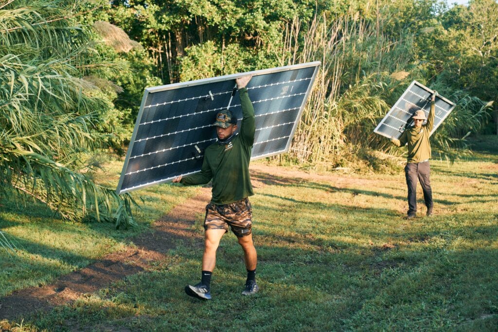 workers carrying solar panels through King Ranch wilderness