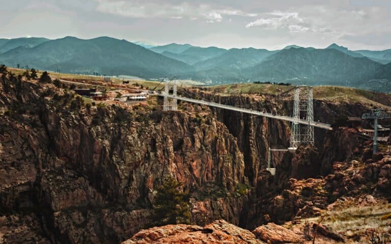 Widescale view of a suspension bridge over the foothills of the Rocky Mountains in Colorado