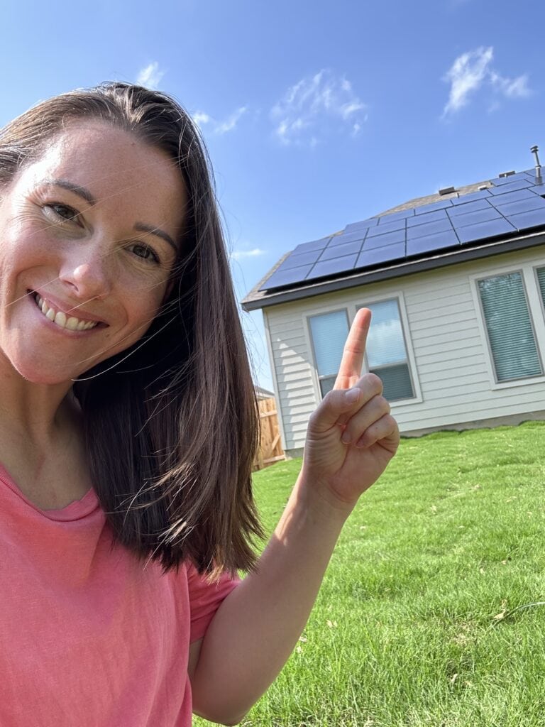 Woman pointing house with solar panels on the roof