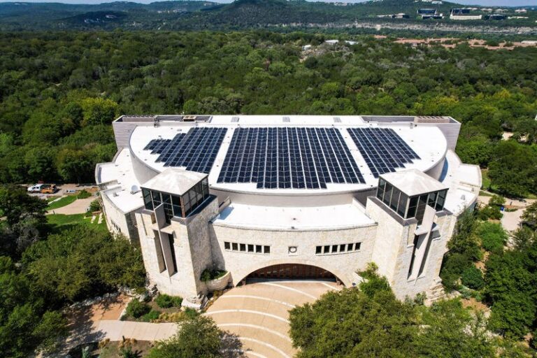Drone view of Riverbend Church, Austin, Texas with solar panels installed on the roof and trees around it