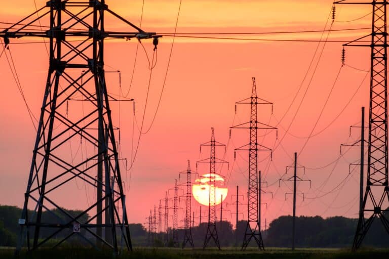 A power grid substation with the sun setting in background.