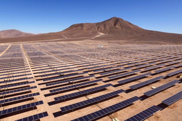 Landscape photo of a large array of solar panel rows in the desert.
