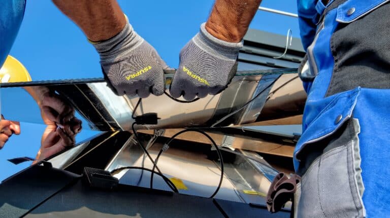 Close-up image of a solar panel technician's hands removing a panel and wiring from a roof