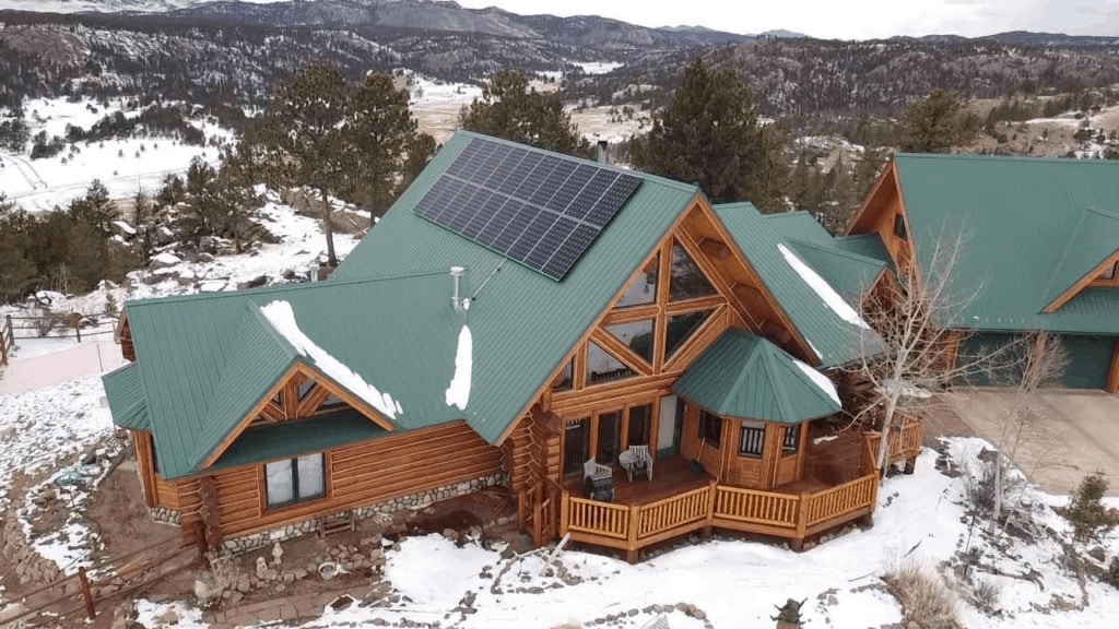 An expansive house during the winter season, equipped with attached solar panels.