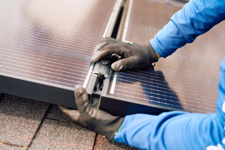 Installer Gloved Hands Squaring Solar Panels on Roof