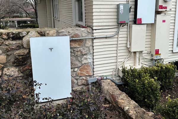 Tesla Powerwall in front. of stone wall