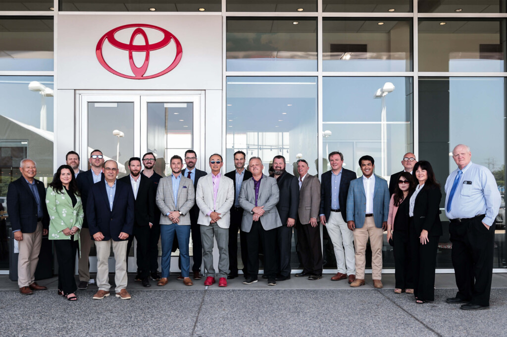 Leaders of Toyota Motor North America, YK Auto Group, and Chuck Hutton Toyota in a group photo in front of Toyota sign